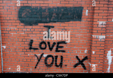'I love you' graffiti on red brick wall with name above painted over, signifying relationship break-up Caerphilly Wales UK Stock Photo
