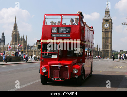 London routemaster bus heads over westminster bridge with the houses of parliament in the background. Stock Photo