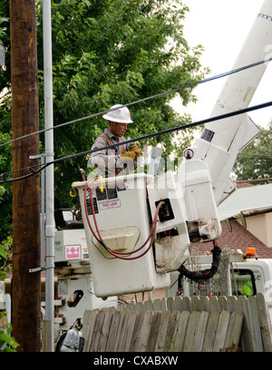 A man working for an Electric Company in a lift bucket stops for a drink of water while installing a new power pole and lines. Stock Photo