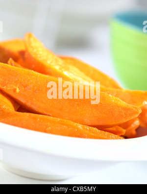 Fresh homemade caramelized sweet potato wedges in white bowl (Selective Focus, Focus one third into the sweet potatoes) Stock Photo