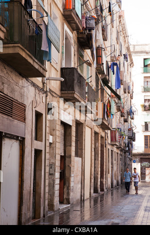 Two young men walk down this freshly washed street, finally turning into one of the apartment buildings in Barcelona, Spain. Stock Photo