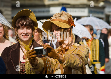 Young ladies in Regency costume photograph themselves during the promenade in Bath city centre during 2012 Jane Austen Festival Stock Photo