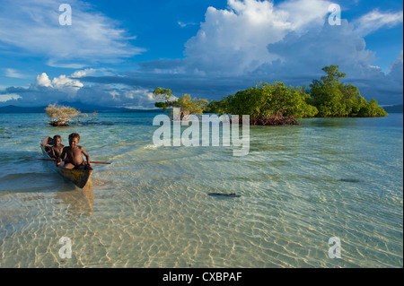 Young boys fishing in the Marovo Lagoon below dramatic clouds, Solomon Islands, Pacific Stock Photo