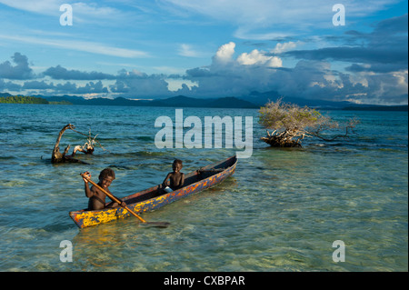 Young boys fishing in the Marovo Lagoon below dramatic clouds, Solomon Islands, Pacific Stock Photo