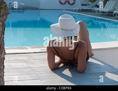 young female relaxing by swimming pool, kamari, santorini, greece Stock Photo
