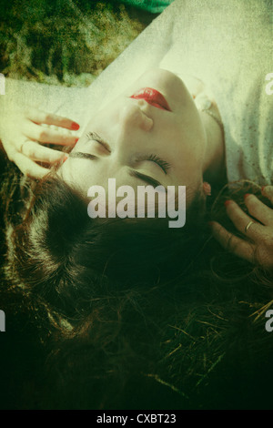Woman Laying on Grass with Head Tilted Back at Viewer Stock Photo