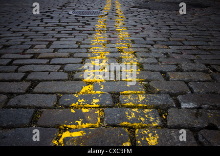 Old cobblestone street and worn yellow lines from New York City Stock Photo