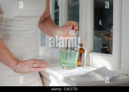 Health issues and people, mature woman with prescription medicine and water. Cropped view Stock Photo