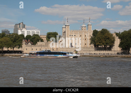 A River Thames 'Thames Clipper' river boat passes the Tower of London, in central London, UK.