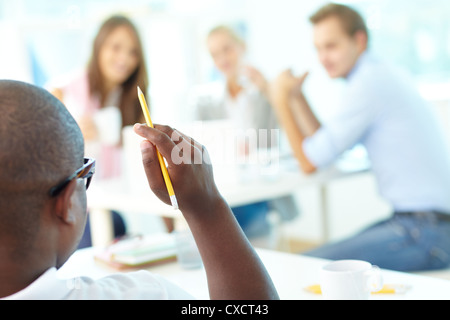 Rear view of African guy holding pencil with group of students looking at him Stock Photo