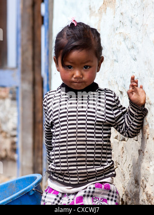 Little Nepali girl standing next to a white wall, Nepal Stock Photo