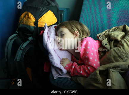 A tired girl sleeping in the cabin during a train journey from Germany to Italy. Austria, Europe. Stock Photo