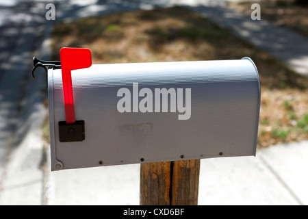 Gray mailbox with raised red flag. Stock Photo