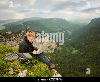 Caucasian man using laptop on remote cliff's edge Stock Photo