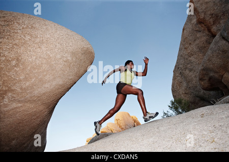 Woman running up boulder in remote area Stock Photo