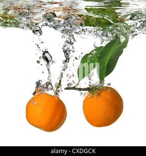 tangerines dropped into water with bubbles on white Stock Photo