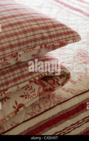 Folded duvet covers in red checked and floral patterned fabric Stock Photo
