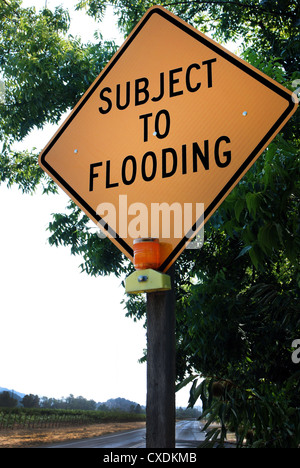 Warning sign that road is subject to flooding and a barrier and road ...