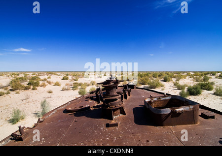 Rusty boats lay still on the dry desert sea bed of the dried Aral sea. Stock Photo