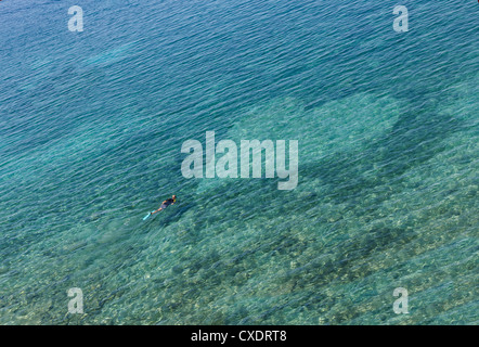 Diver with mask at sea entering a heart-shaped area from sand, shot from a high point of view Stock Photo