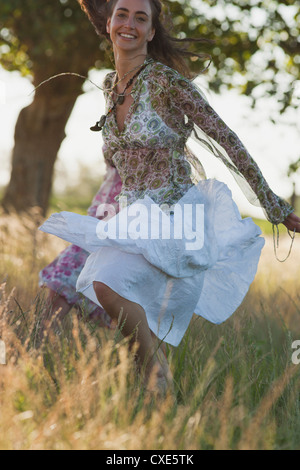Young woman jumping in field, smiling Stock Photo