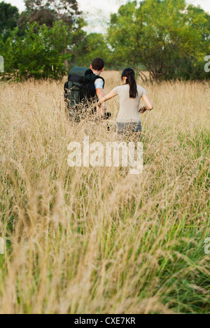 Couple hiking in field, rear view Stock Photo