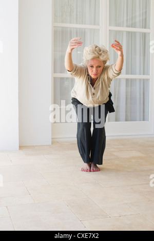 Mature woman doing yoga chair pose Stock Photo