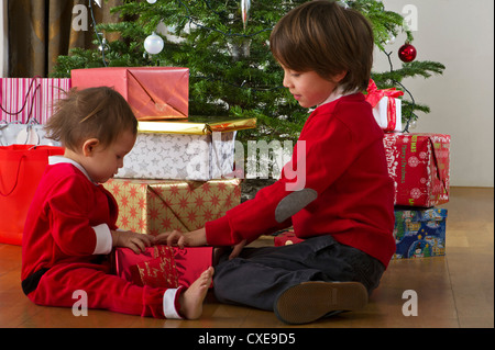 Young brother and sister opening Christmas gift together Stock Photo