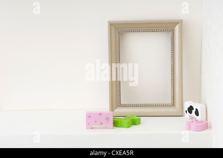 Empty picture frame and child's toys on shelf Stock Photo