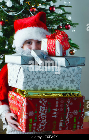 Boy holding stack of Christmas presents Stock Photo