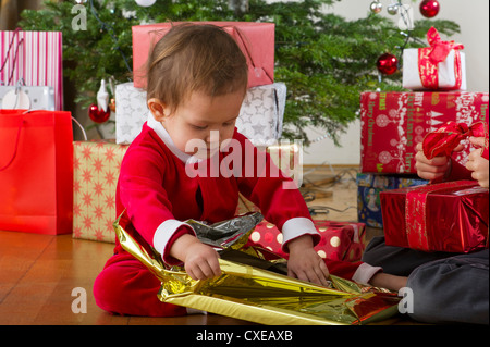 Baby girl unwrapping Christmas present Stock Photo