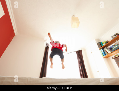 Four year old boy bouncing on the bed. Stock Photo