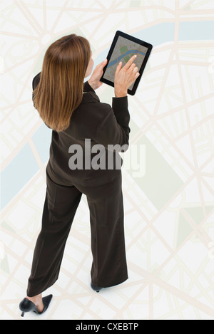 Woman looking at map on digital tablet while walking on large map Stock Photo