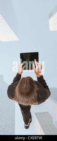 Businesswoman using digital tablet while walking on superimposed image of skyscrapers Stock Photo