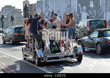 Group of men & women enjoy energetic tour around London on Pedi bus also known as party bike beer cycle pedal crawler pedal pub party bike England UK Stock Photo