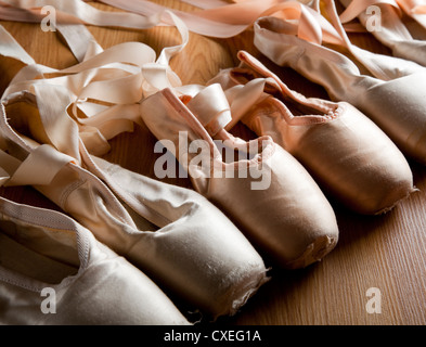 A group or background of used ballet pointe shoes or slippers on a wooden floor Stock Photo