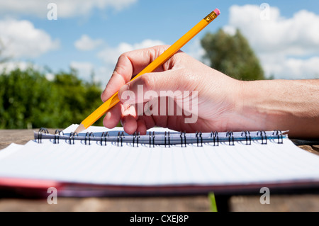 Writing doodling with a pencil in a notebook outside. Stock Photo