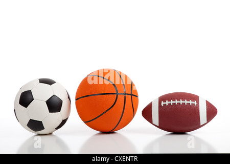 Assorted sports balls on a white background including a soccer ball, a basketball and an American football Stock Photo