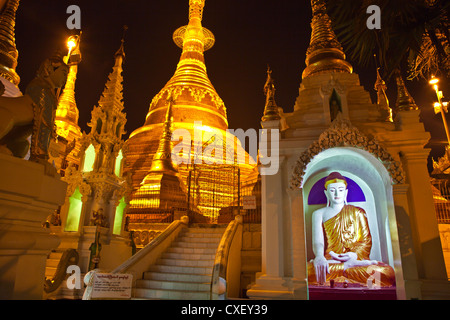 A BUDDHA STATUE and the main ZEDI of the SHWEDAGON PAGODA which dates from 1485 is gilded every year - YANGON, MYANAMAR Stock Photo