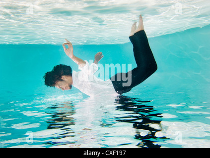 Mixed race man in clothes underwater in swimming pool Stock Photo