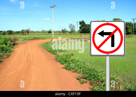 don't turn left sign with a left curved soil road Stock Photo