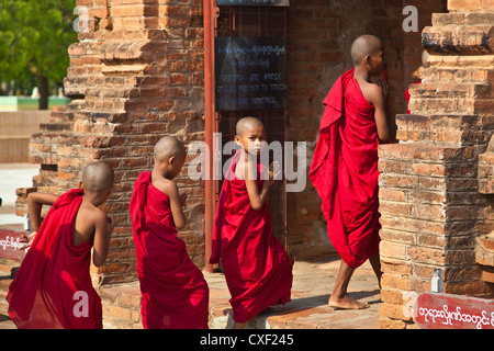 Young BUDDHIST MONKS enter one of the stupas of the ALO PYI GROUP - BAGAN, MYANMAR Stock Photo