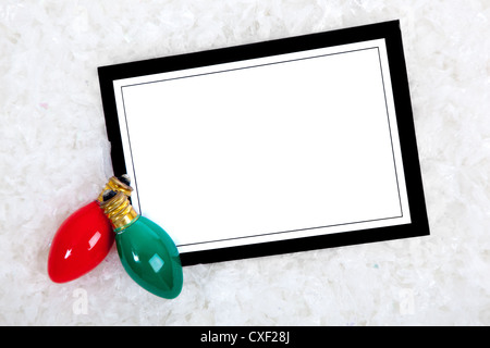 Blank note-card with a red and green Christmas light sitting on snow Stock Photo