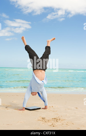 businessman doing handstand on the beach Stock Photo