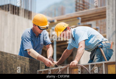 Authentic construction workers collaborating in the installation of cement formwork frames Stock Photo