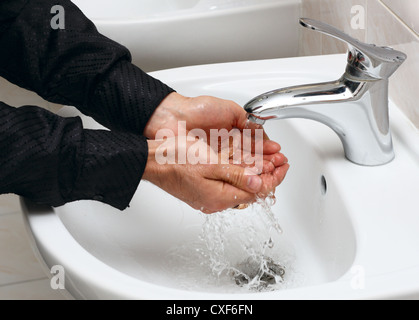 Man washing his hands in running water, in a public toilet. Stock Photo