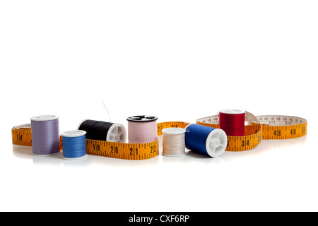 row of spools of thread with a tape measure on a white background Stock Photo