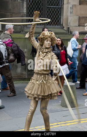 Gold-painted woman spinning hoops during Festival Fringe in Edinburgh, Scotland. Stock Photo