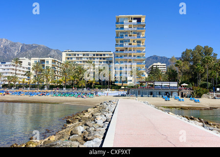Pier, beach and apartment buildings in resort town of Marbella on Costa del Sol in Spain, Andalusia, Malaga province. Stock Photo