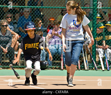 Young boy with his coach running to first base after making a hit during a Miracle League softball game. Stock Photo